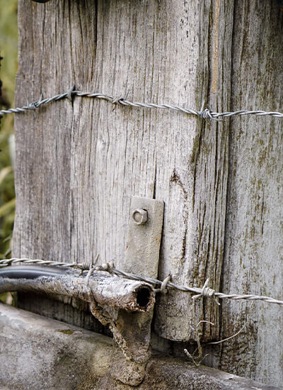 Photo d'un poteau en bois avec du barbelé.