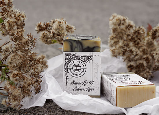 Photo de savons artisanaux sur un papier de soie avec des fleurs séchées.