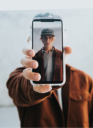 Photo d'un home tenant un téléphone portable à bout de bras devant son visage.